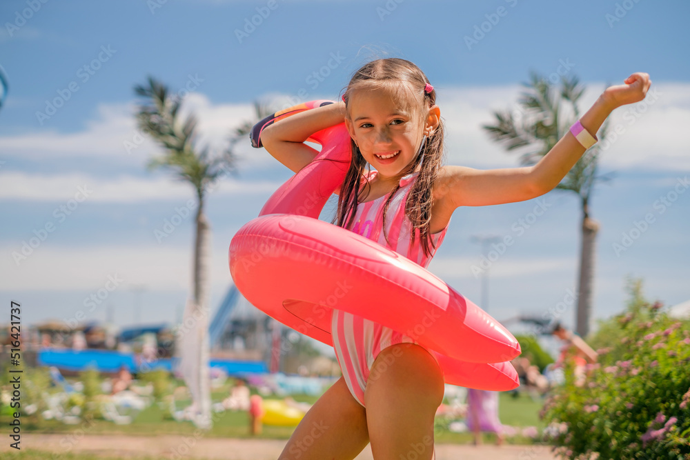 A beautiful girl holds a flamingo-shaped lifebuoy against the backdrop of a resort with palm trees and blue sky. Tourist holidays A beautiful girl holds a flamingo-shaped lifebuoy against the backdrop of a resort with palm trees and blue sky. Tourist holidays