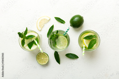 Caipirinha, Mojito cocktail, vodka or soda drink with lime, mint and straw on table background. Refreshing beverage with mint and lime in glass top view flat lay