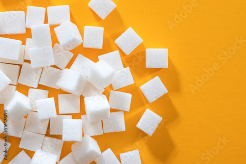 Background from sugar cubes on a yellow background. Refined sugar, top view