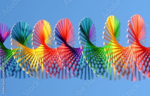 Closeup of an open slinky spring rainbow circle against blue sky background photo