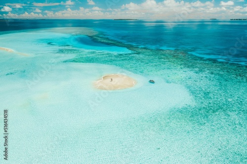 Aerial view of a boat approaching the people on the sandbank in the Maldives