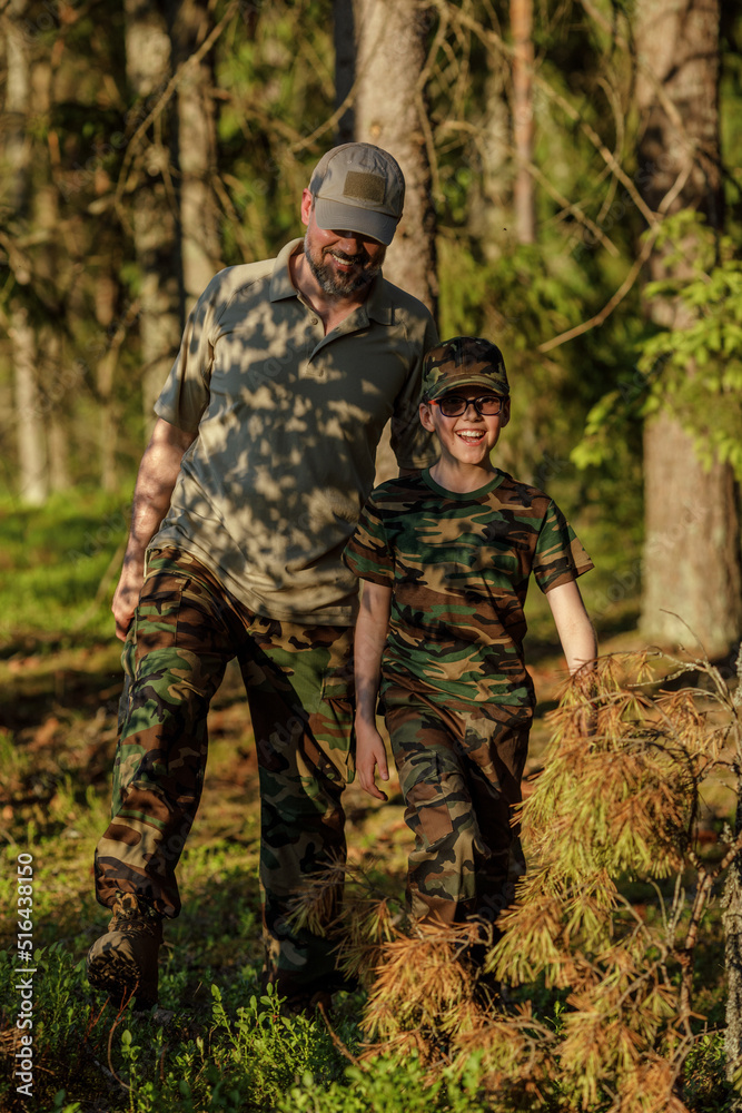 Father and son in military clothes spending time together in the woods. The concept of adventure, travel, tourism and camping