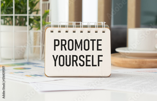 A sign with the inscription PROMOTE YOURSELF on the table with office supplies