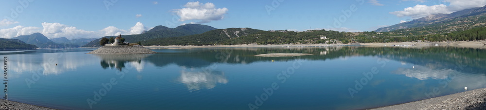 panoramic view  of the mirror reflection of  the  mountains and island of  bay st michel in serre ponçon lake alps france