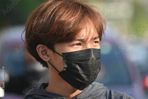 Portrait of a Southeast Asian guy wearing a black mask in a blurred background