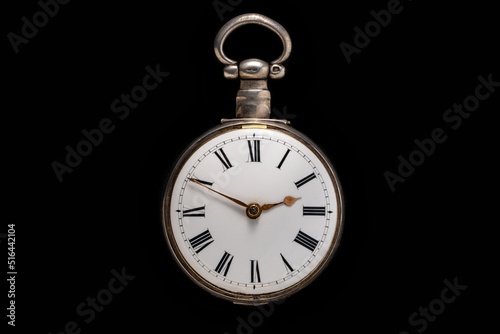 Dial of silver antique pocket watch on isolated black background. Old mechanical clock. Round retro pocketwatch with minute and hour hands. Vintage expensive watch. Symbol of time, luxurious life.
