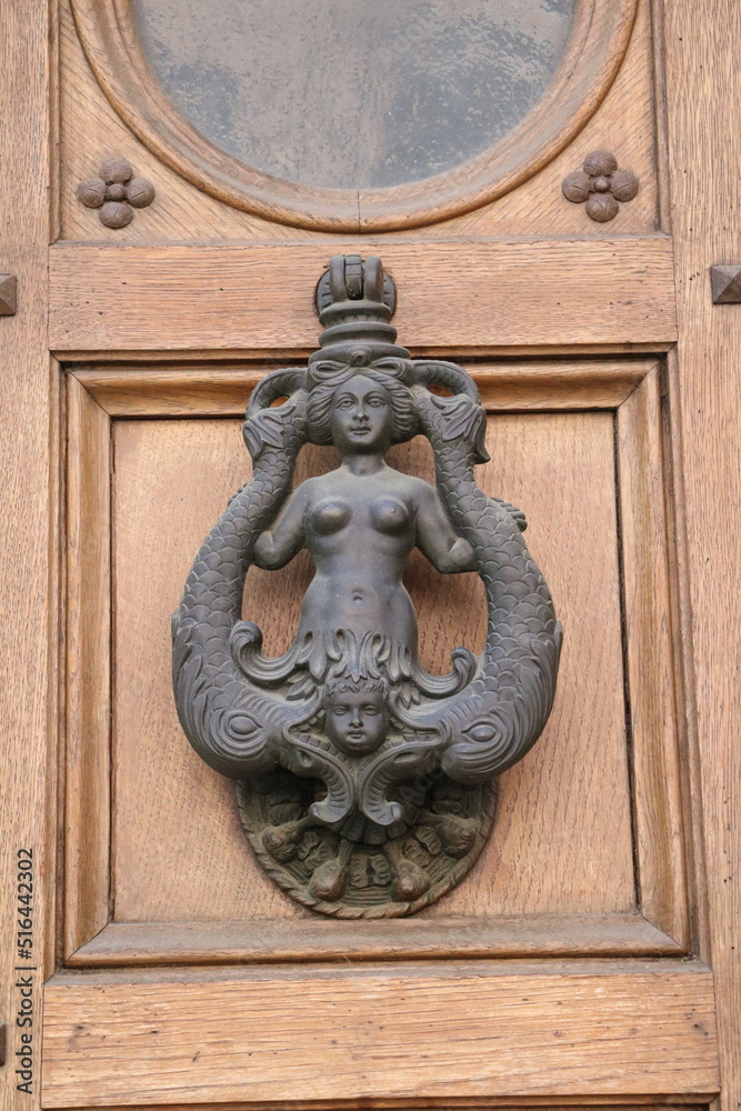 Antique door knocker on old wooden door, Italy