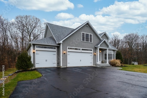 Gray-walled suburban house with white asphalt driveway photo