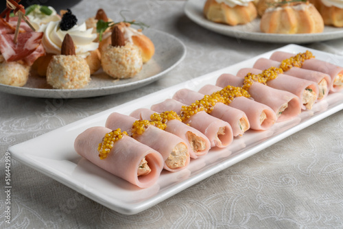 Stuffed ham rolls garnished with Dijon mustard. Plate on the festive table.