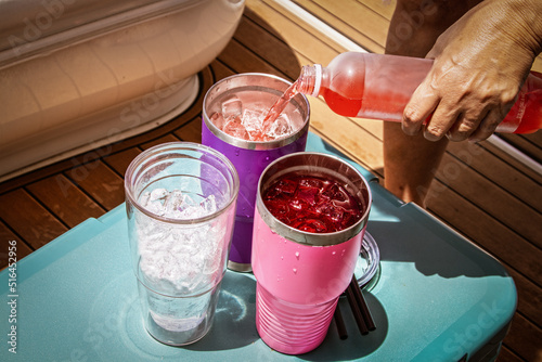 Boat Drinks poured from a bottle into insulated glasses with ice sitting on an ice chest on a luxury boat.