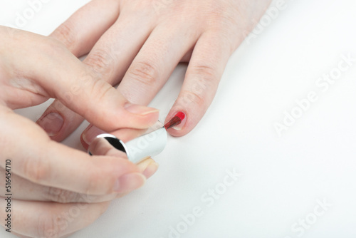 A woman applies polish to her little fingernail.
