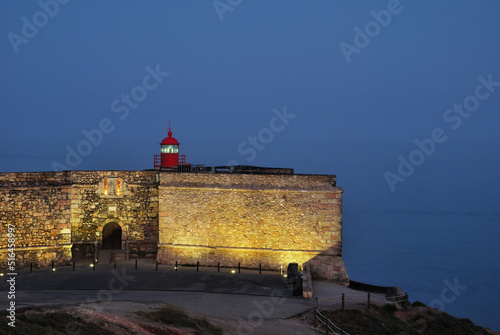 Forte de São Miguel Arcanjo com farol no topo ao amanhecer, Nazaré, Portugal, mar e luzes acesas photo