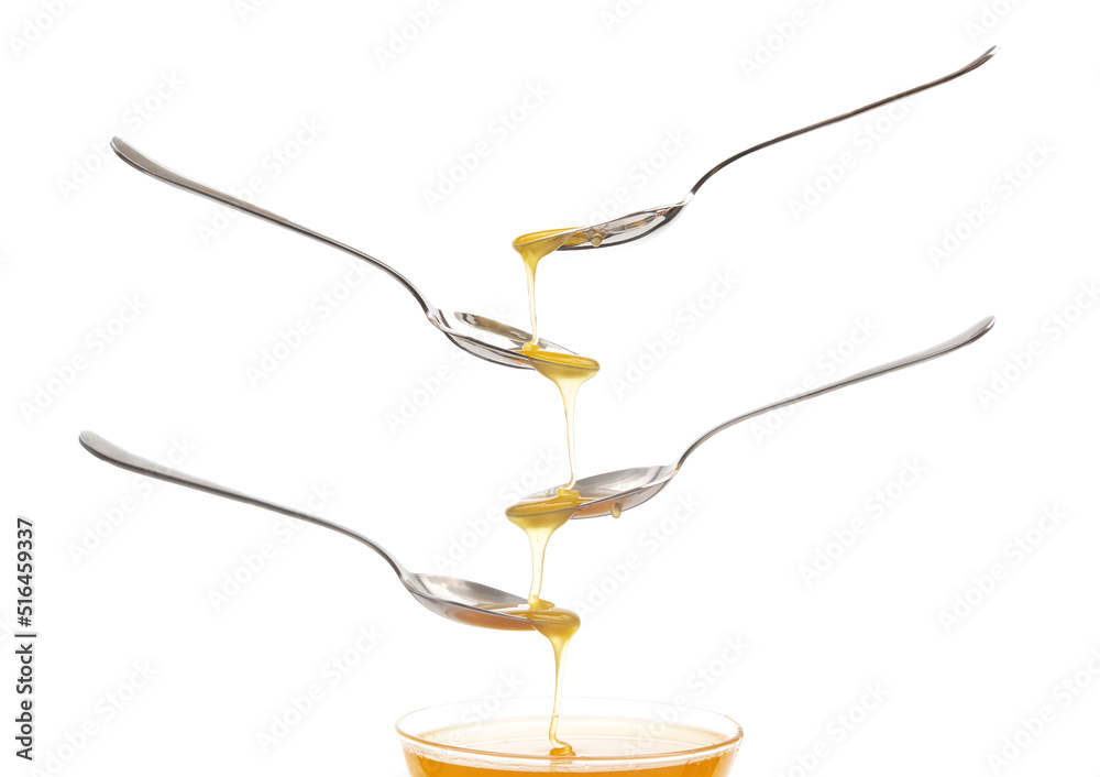 Fresh floral honey drips from a spoon into a spoon on a white background. Organic vitamin food.