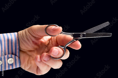 hand holds scissors on a dark background. tailor and barber profession