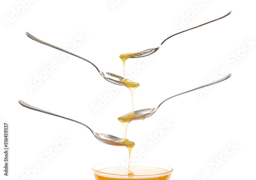 Fresh floral honey drips from a spoon into a spoon on a white background. Organic vitamin food.