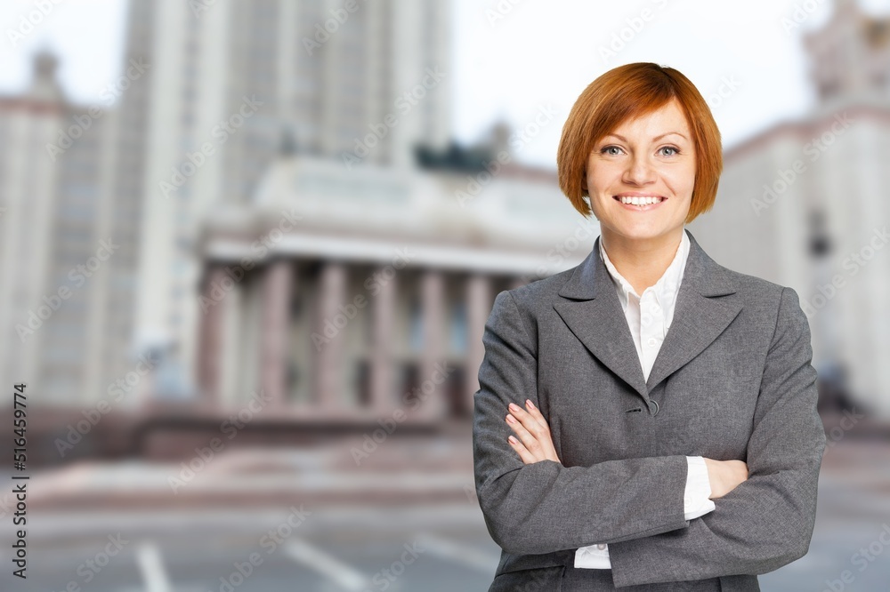 A serious elegant businesswoman standing on the street with arms crossed. Success concept. A serious elegant businesswoman standing on the street with arms crossed. Success concept.