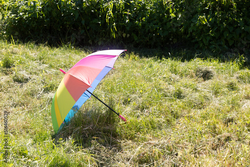 A multicolored umbrella is lying on the grass.Summer background.