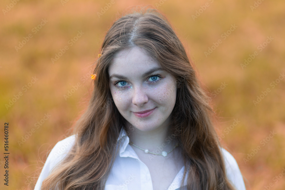 Naklejka premium Portrait of a beautiful girl with red hair and freckles on her face in an autumn park.