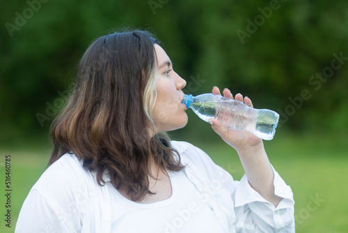 A woman with a bottle of clean water. A woman drinks water from a bottle.
