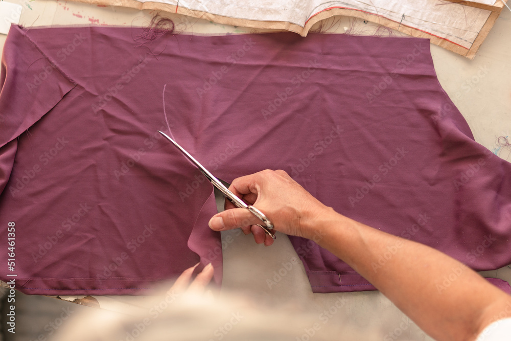 woman cutting fabric along the line drawn with chalk