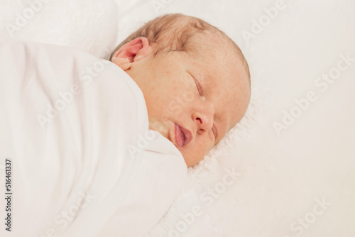 Newborn baby in crib on white blanket, baby portrait 7 days old. The first days of life