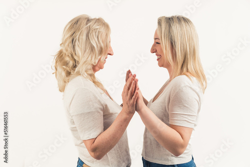 Two middle-aged mature women standing towards each other, touching each other with foreheads and holding hands. High quality photo
