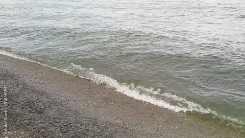 gentle waves on a beach full of gravel, calm day