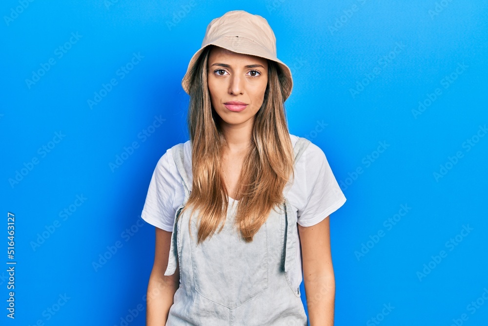 Beautiful hispanic woman wearing explorer hat with serious expression on face. simple and natural looking at the camera. Beautiful hispanic woman wearing explorer hat with serious expression on face. simple and natural looking at the camera.