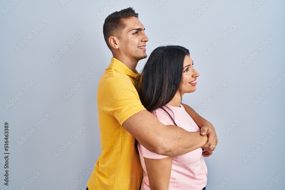 Young couple standing over isolated background looking to side, relax profile pose with natural face and confident smile. Young couple standing over isolated background looking to side, relax profile pose with natural face and confident smile.