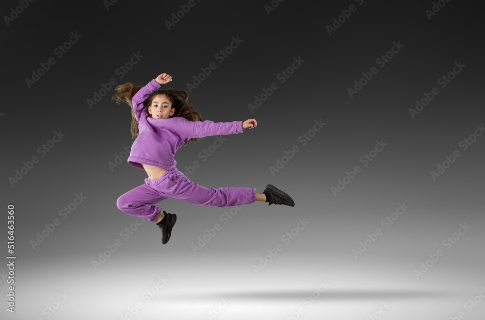 Concentrated athletic girl jumping during running. Modern healthy and sports youngster lifestyle.