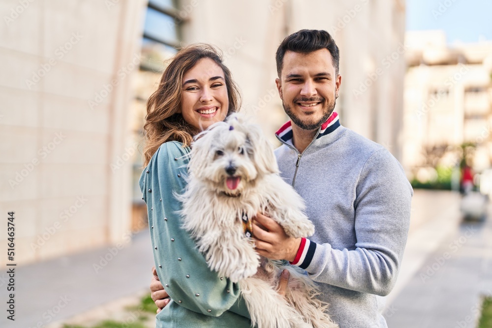 Man and woman holding dog hugging each other at street Man and woman holding dog hugging each other at street