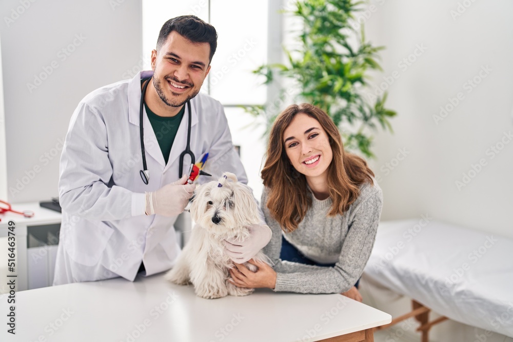 Man and woman veterinarian examining dog using otoscope at veterinary clinic