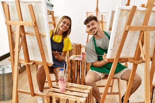 Young hispanic artist couple smiling happy drawing at art studio.