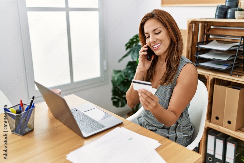 Young latin woman business worker talking on the smartphone holding credit card at office Young latin woman business worker talking on the smartphone holding credit card at office