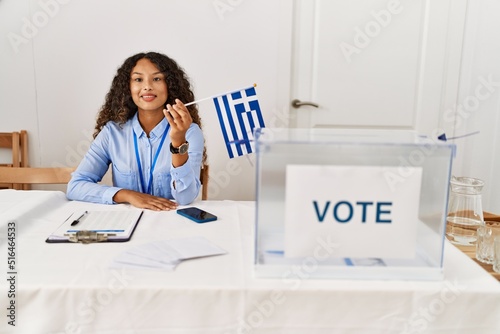 Young latin woman smiling confident holding greece flag working at electoral college