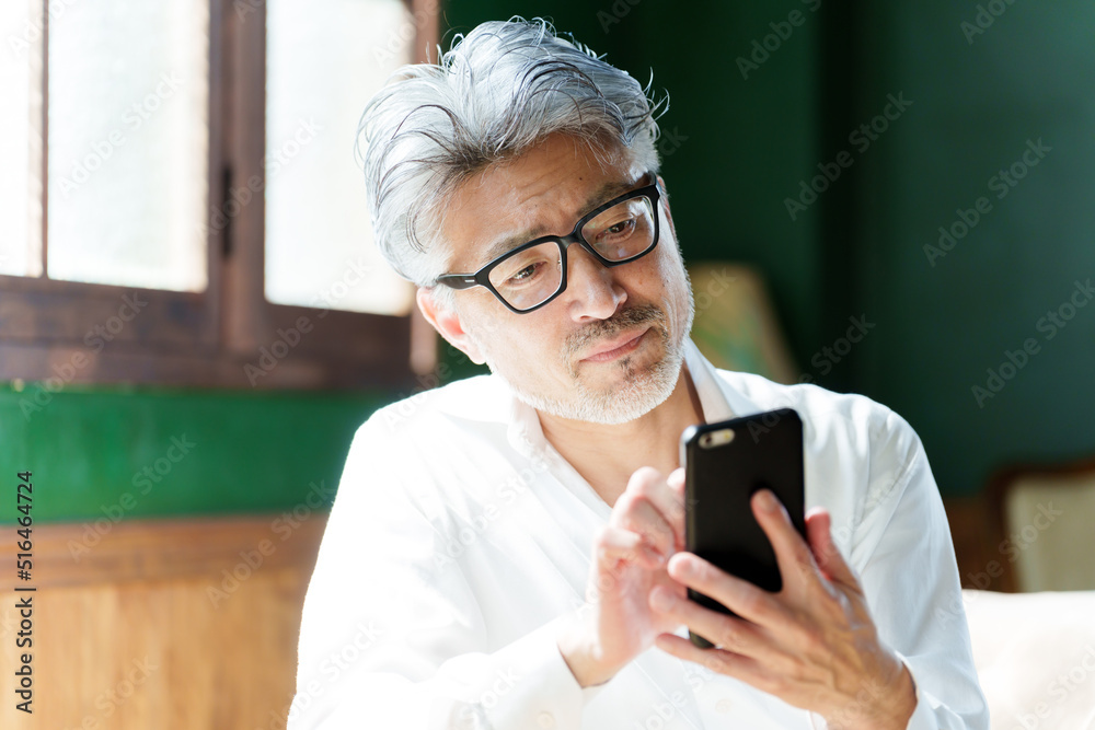 室内でスマートフォンを使うミドル男性 室内でスマートフォンを使うミドル男性