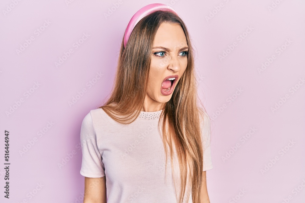Young blonde girl wearing casual clothes angry and mad screaming frustrated and furious, shouting with anger. rage and aggressive concept.