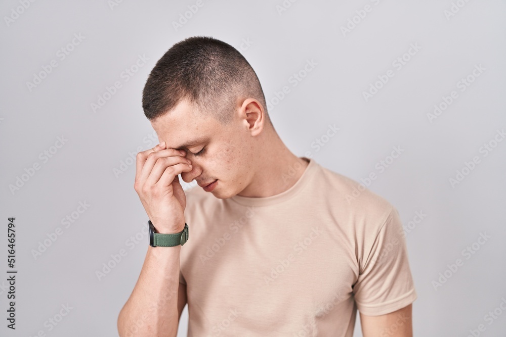 Young man standing over isolated background tired rubbing nose and eyes feeling fatigue and headache. stress and frustration concept. Young man standing over isolated background tired rubbing nose and eyes feeling fatigue and headache. stress and frustration concept.