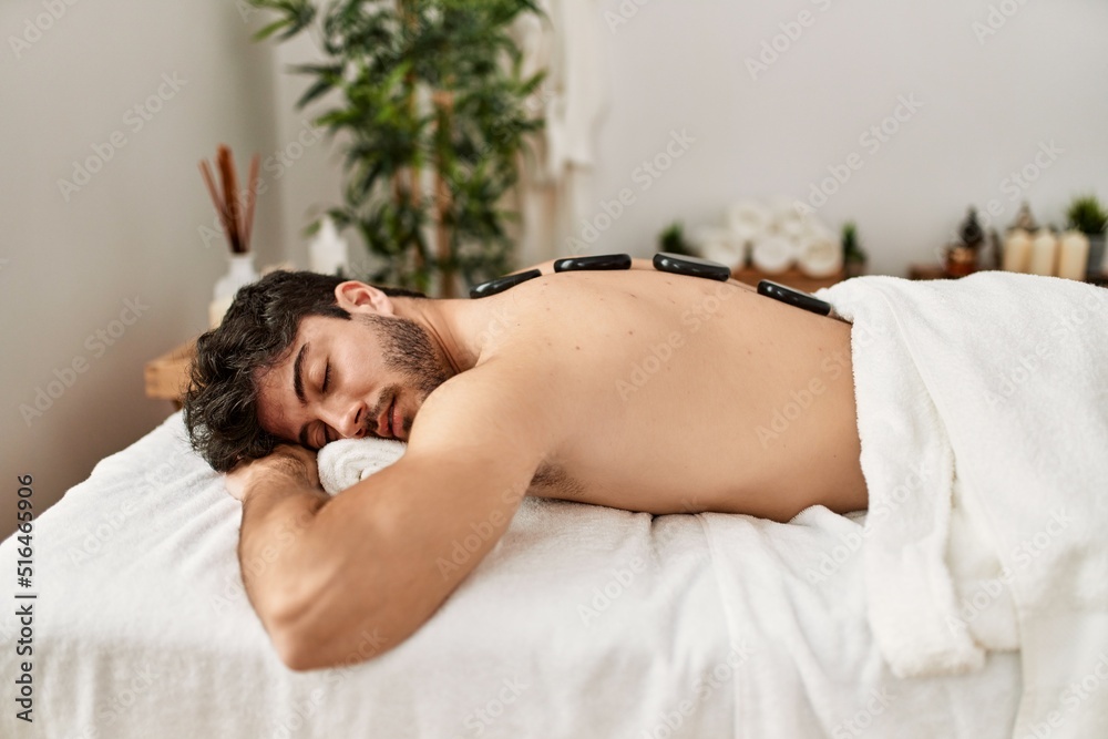 Man reciving back massage with black stones at beauty center. Man reciving back massage with black stones at beauty center.