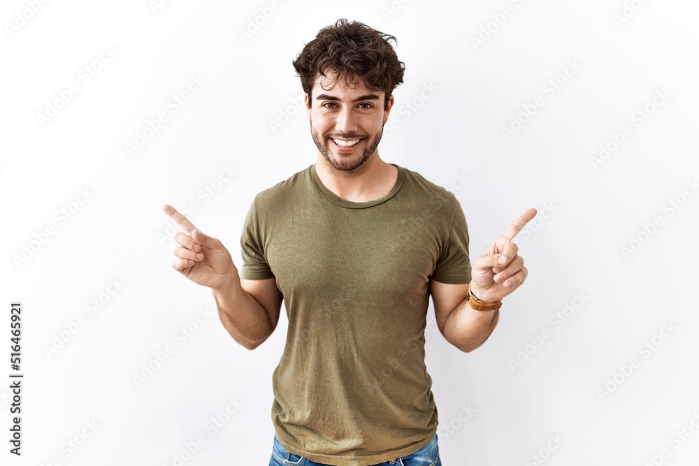 Hispanic man standing over isolated white background smiling confident pointing with fingers to different directions. copy space for advertisement