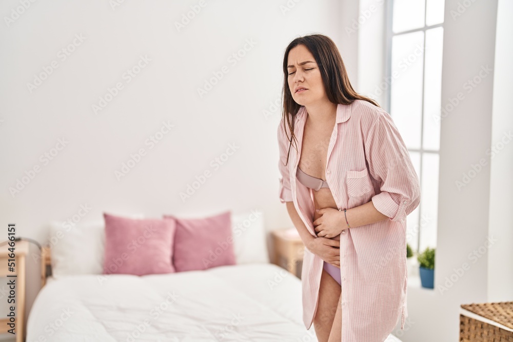 Young woman suffering for menstrual pain standing at bedroom Young woman suffering for menstrual pain standing at bedroom