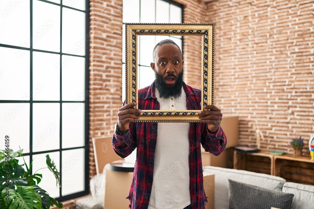 Obraz premium African american man putting face in empty frame afraid and shocked with surprise and amazed expression, fear and excited face.