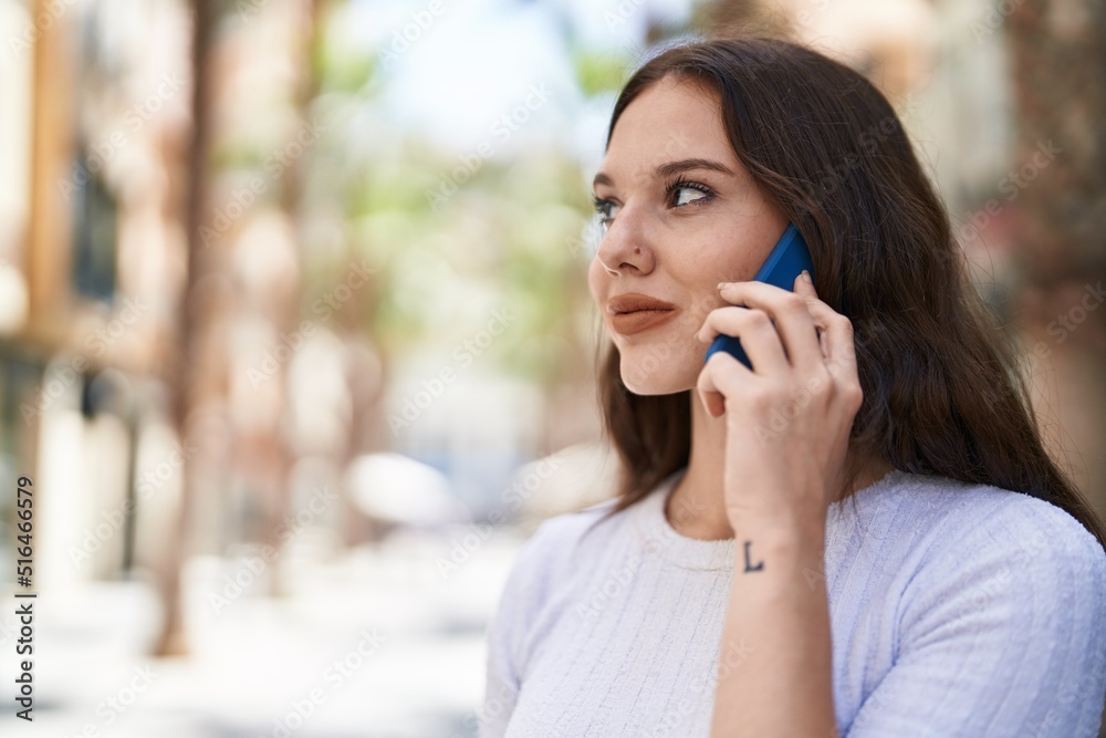 Young woman smiling confident talking on the smartphone at street