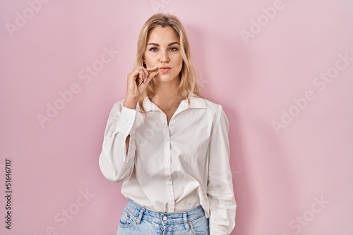 Young caucasian woman wearing casual white shirt over pink background mouth and lips shut as zip with fingers. secret and silent, taboo talking