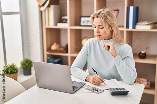 Young blonde woman sitting on table working at home