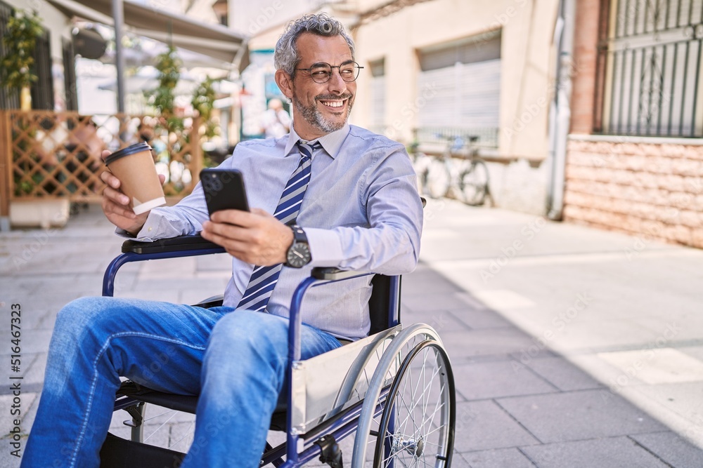 Middle age hispanic man sitting on wheelchair using smartphone at street Middle age hispanic man sitting on wheelchair using smartphone at street