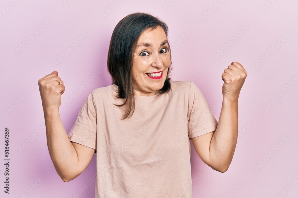 Middle age hispanic woman wearing casual clothes celebrating surprised and amazed for success with arms raised and open eyes. winner concept. Middle age hispanic woman wearing casual clothes celebrating surprised and amazed for success with arms raised and open eyes. winner concept.