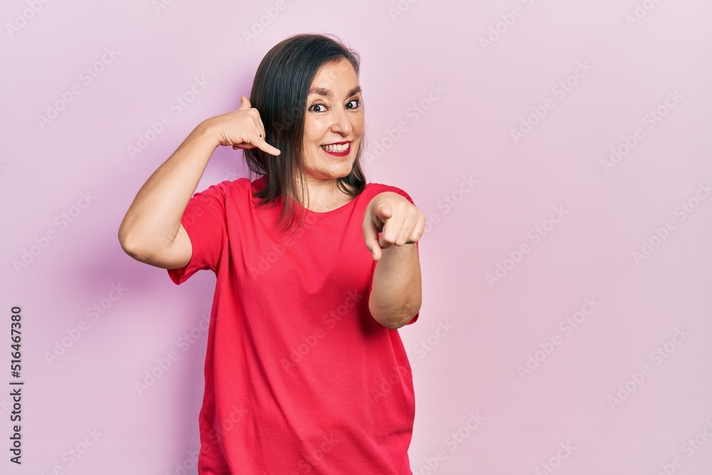 Middle age hispanic woman wearing casual clothes smiling doing talking on the telephone gesture and pointing to you. call me. Middle age hispanic woman wearing casual clothes smiling doing talking on the telephone gesture and pointing to you. call me.