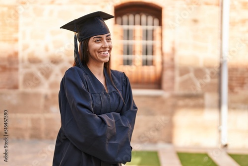 Young hispanic woman wearing graduated uniform standing with arms crossed gesture at university photo