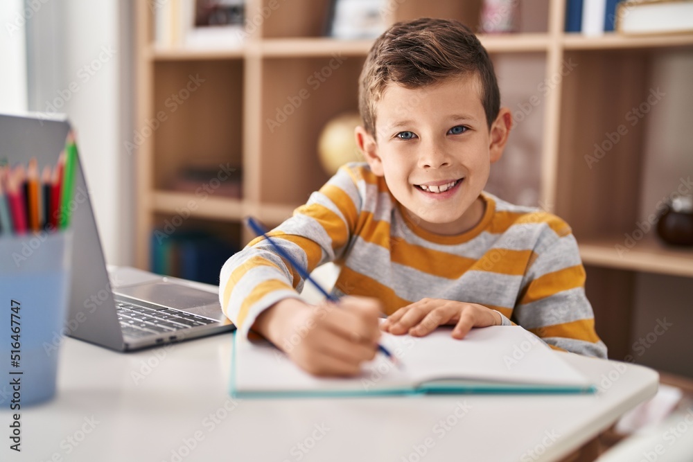 Blond child studying sitting on table at home Blond child studying sitting on table at home